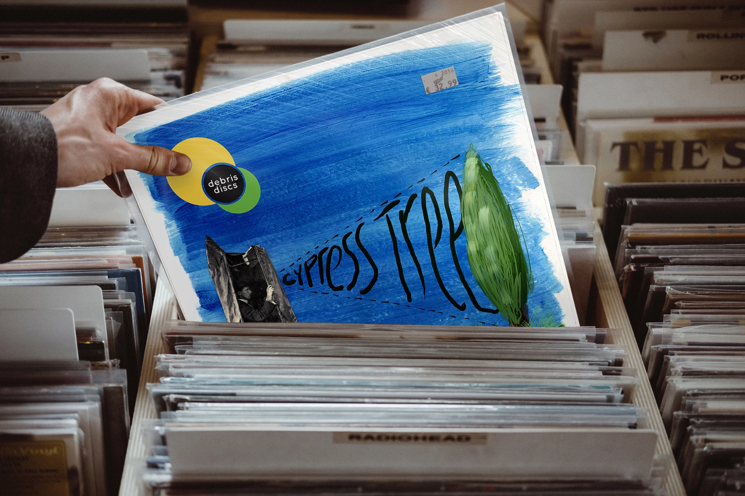 Debris Discs Cypress Tree artwork mock up in a record store rack being picked up by a hand. Album design by Gavin Stretch of Mode=Create
