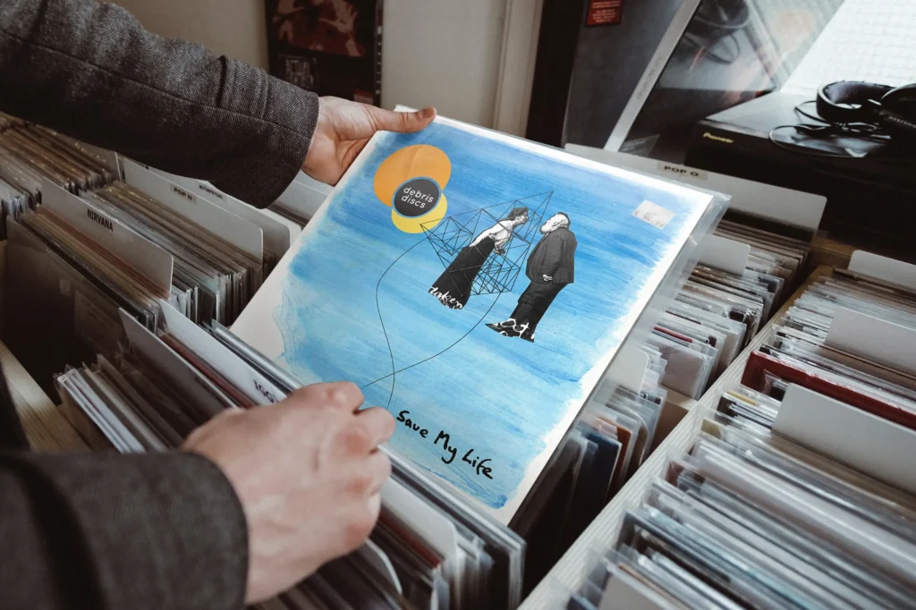 Debris Discs Save My Life single being held in a record shop. Music artwork design by Gavin Stretch of Mode=Create